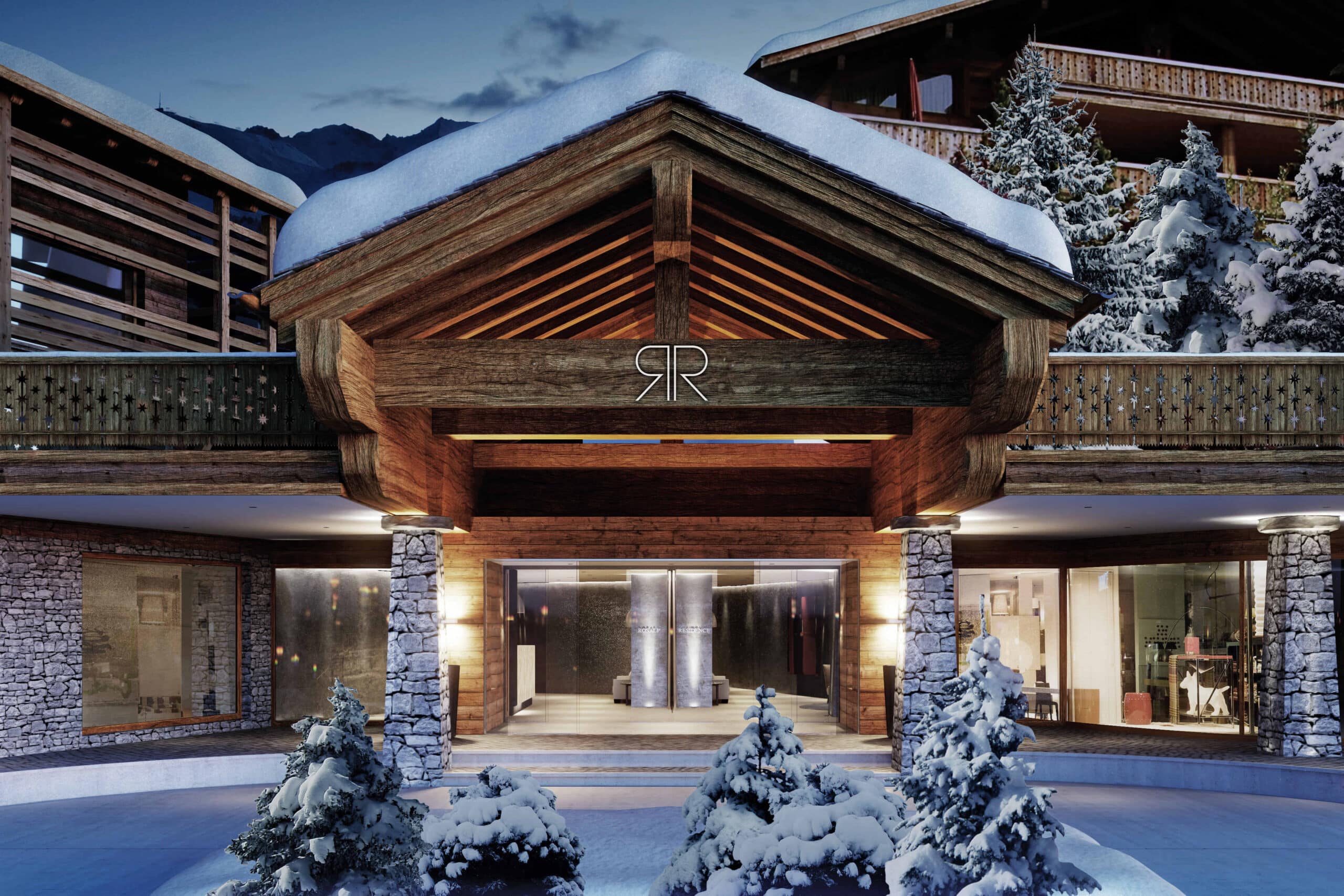 A luxurious mountain hotel entrance, epitomizing luxury travel, features a wooden and stone facade adorned with snow. The building glows warmly beneath a snowy blanket, encircled by snow-laden pine trees, crafting a cozy winter retreat. David Pearson Travel